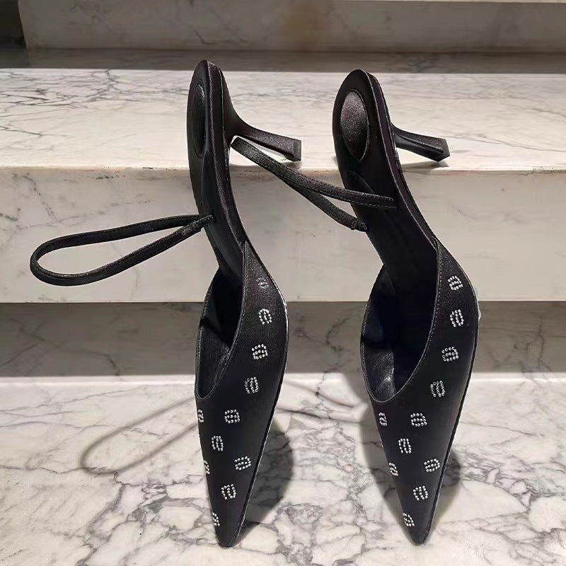 Sandali Valstrend con tacco a spillo, lettere di strass, punta affilata e cinturino satinato, con dettagli sexy e trasparenze.