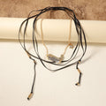 Collana lunga multi-strato in metallo alla moda, stile trendy, con dettagli eleganti e moderni, indossata su sfondo neutro.