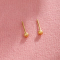 Piccoli orecchini a perno rotondi in oro placcato rame, finitura opaca e lucida, stile minimalista e raffinato.