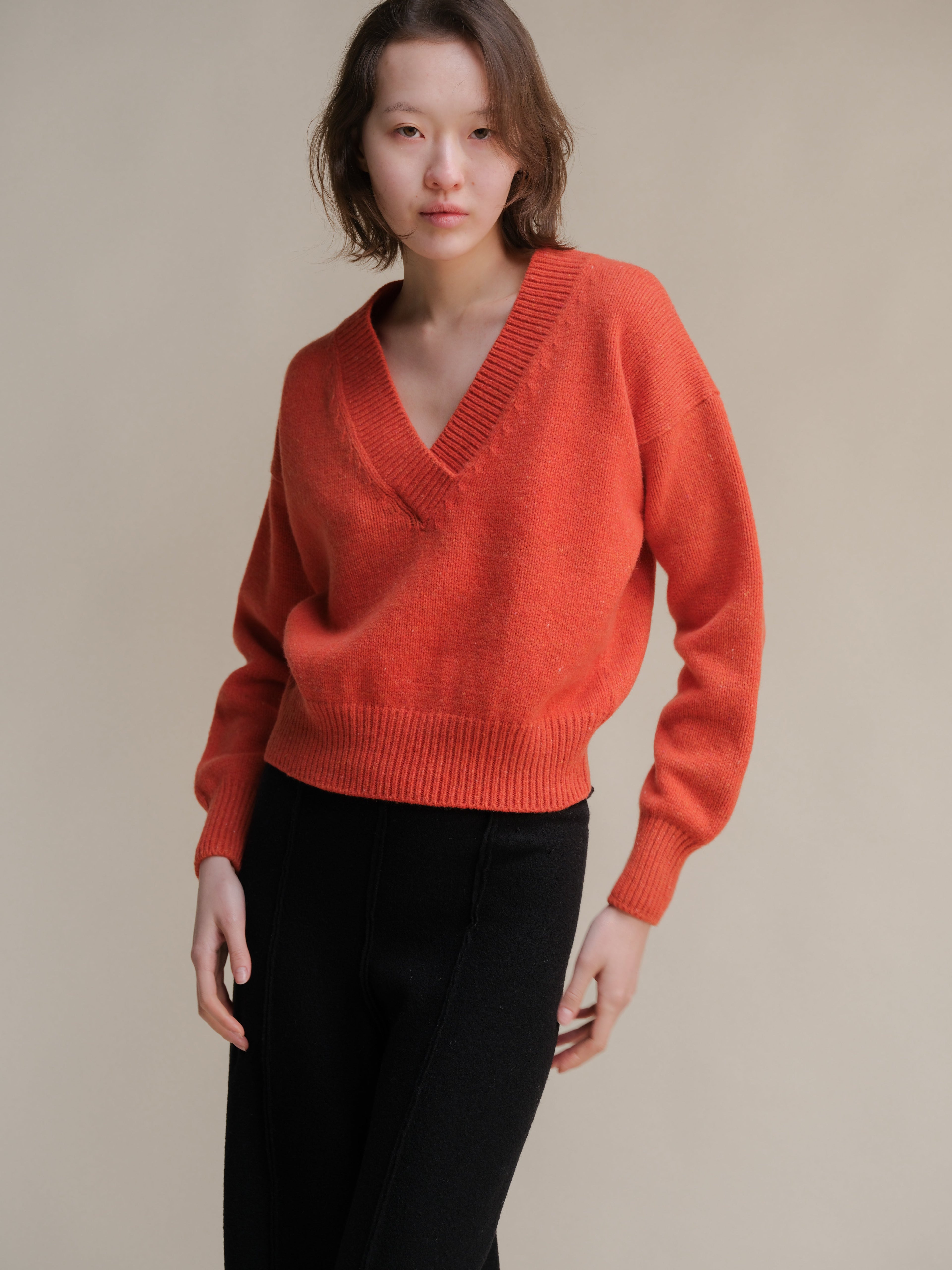 Maglione cropped in tweed color caramello di Lèmme, con doppio scollo a V, in maglieria elegante e alla moda.