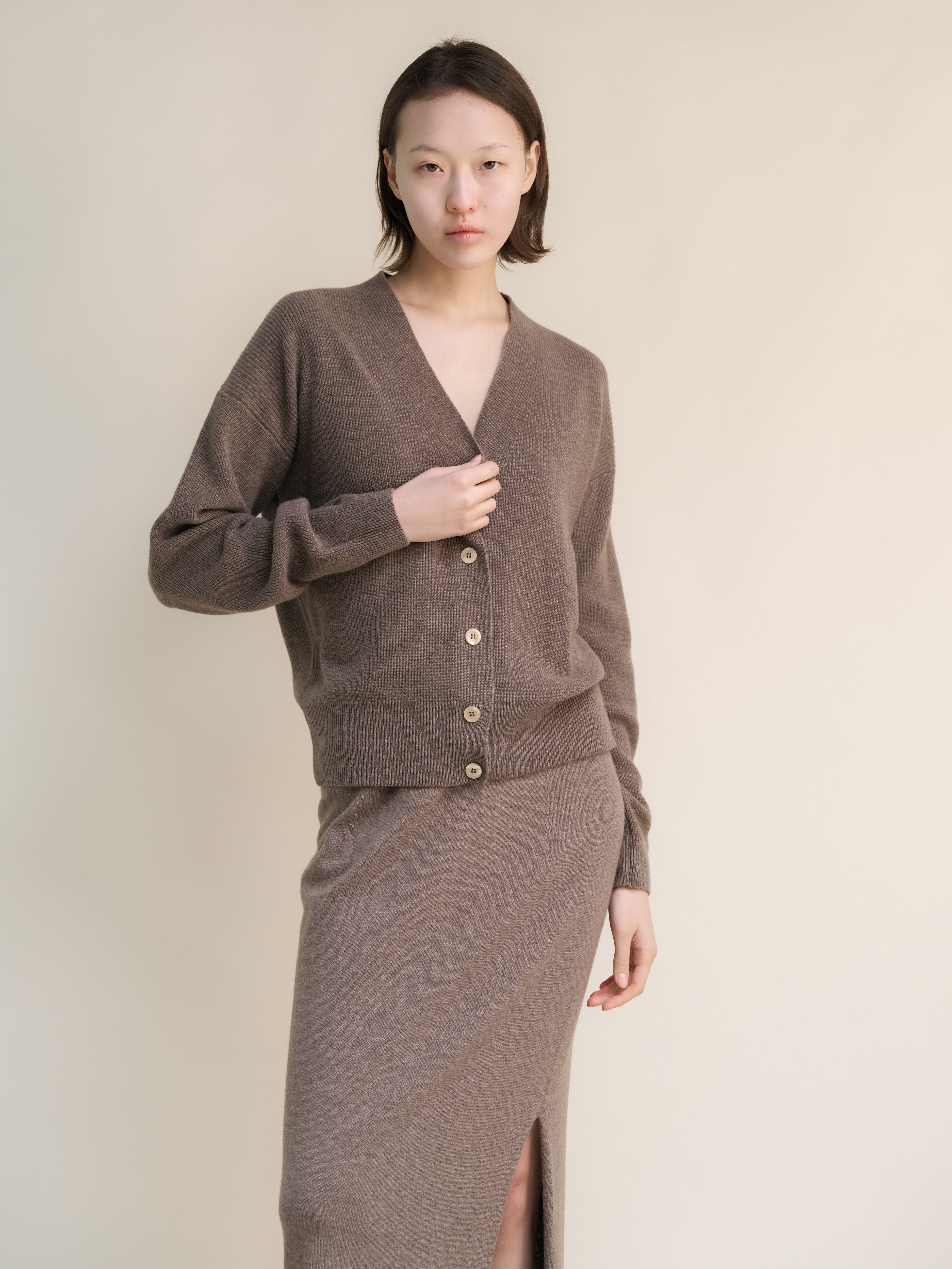 Cardigan in misto cashmere e lana, a costine, di Lèmme, in grigio acciaio, indossato con collo a V e maniche lunghe.