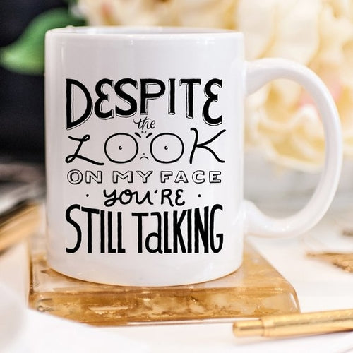Tazza nera Sajishop con scritta "Despite The Look On My Face, You're Still Talking" in ceramica da 11 oz